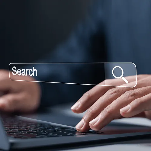 Hands typing a query into a search bar on a laptop